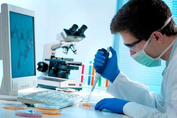 Home 3 Medical professional in a lab coat and mask conducting laboratory tests at Chambana Urgent Care