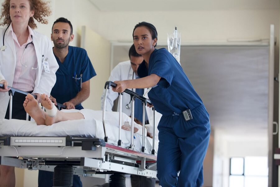 Home 2 Healthcare professionals attending to a patient on a hospital bed, providing urgent medical care in a clinical setting.