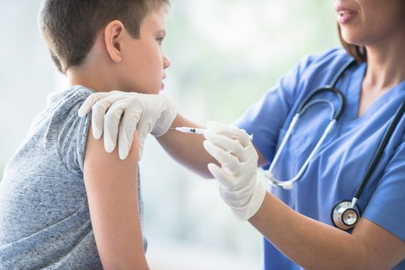 Home 6 Nurse administering a vaccination to a young boy at Chambana Urgent Care.